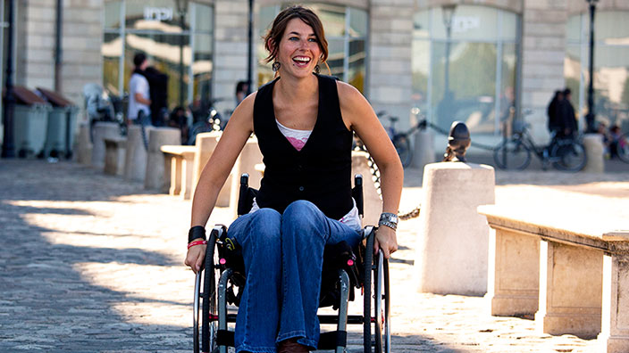 Une femme en fauteuil roulant sourire aux lèvres