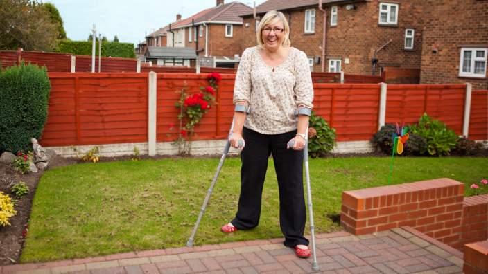 Women with crutches smiling in her backyard 