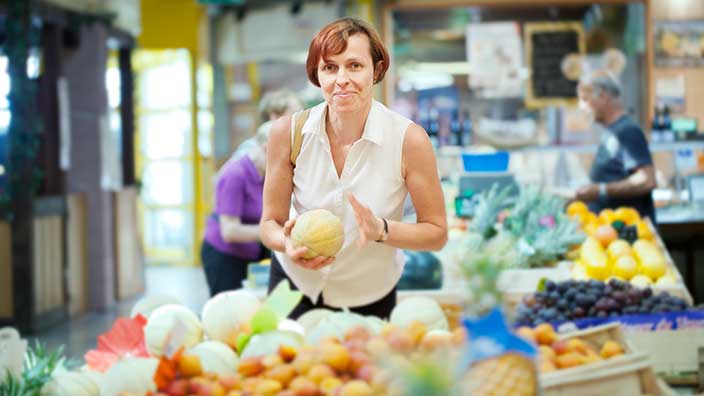 Woman in grocery store picking fruit