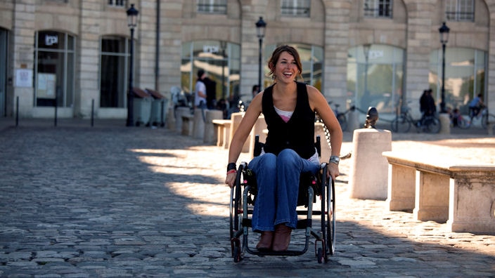 Women in a wheelchair smiling outside