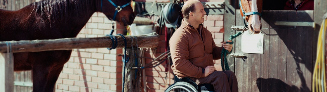 Un homme en fauteuil roulant caressant un cheval